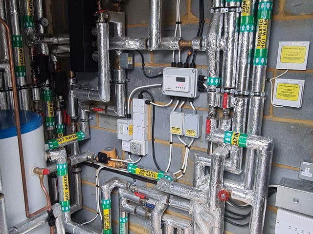 Commercial plant room with labelled heating and domestic hot water pipework